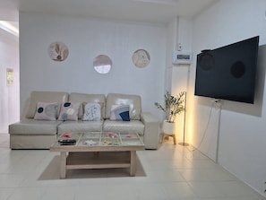 A modern living room with a sofa, coffee table, wall-mounted TV, and decorative wall art.