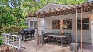 A covered patio with a grill, seating, and a pergola.