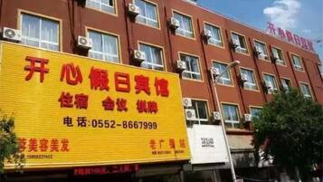A hotel with a yellow signboard displaying contact information and services.