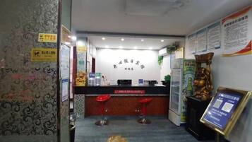 A reception area with a counter, two red bar stools, and a wall with informational posters.