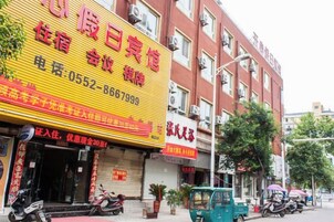 Un hotel con un llamativo letrero amarillo, fachada de color rojo y varias motocicletas estacionadas.