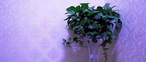 A potted plant on a white stand against a patterned wall.
