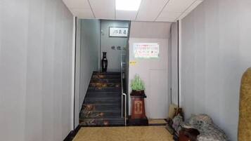 A hallway with a staircase, a reception desk, and a bulletin board.