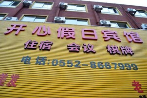 A yellow sign with Chinese characters and a phone number for a hotel.