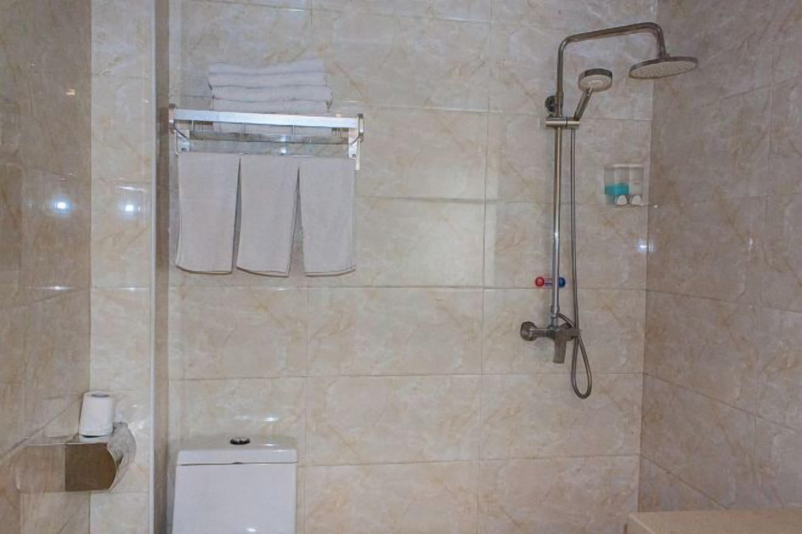 Un baño con ducha, inodoro y toallero.