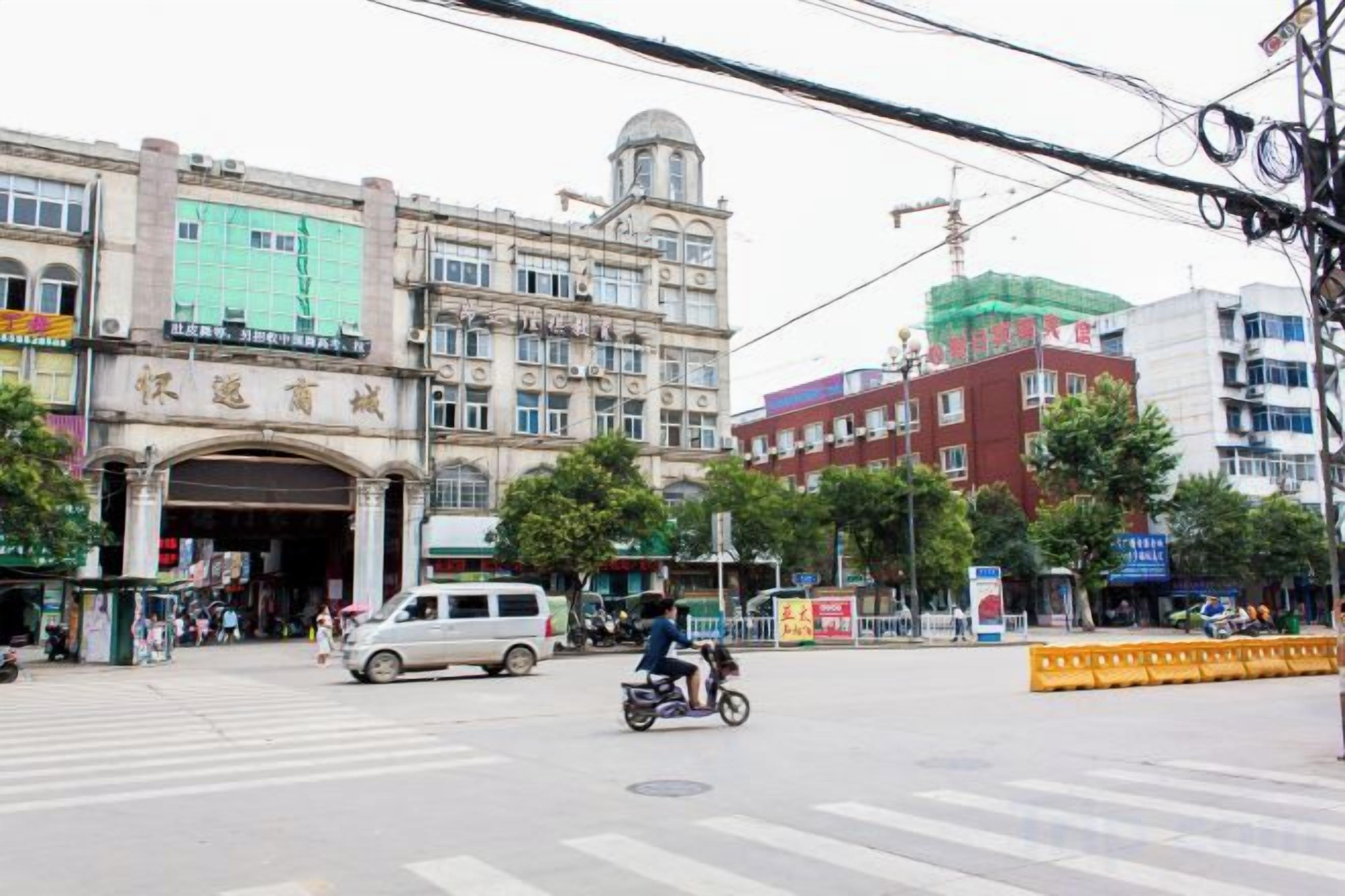 A street intersection with a building featuring an ornate entrance, a pedestrian crossing, and a motorcycle in motion.