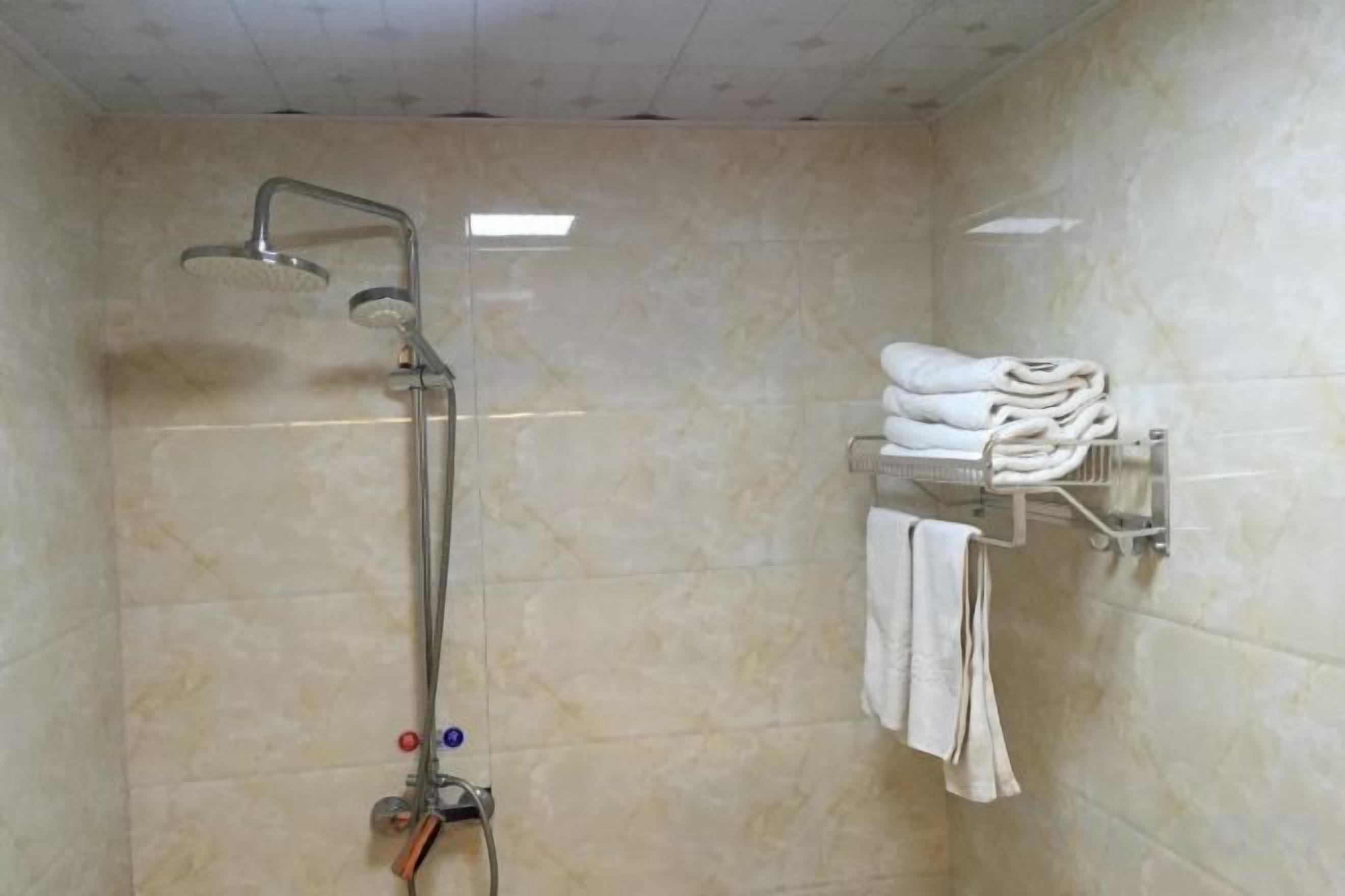 Une salle de bain équipée d’une douche, d’un porte-serviettes et d’un distributeur de serviettes fixé au mur.