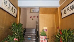 L’entrée d’un hôtel, avec un escalier, des calligraphies encadrées et des plantes en pot.