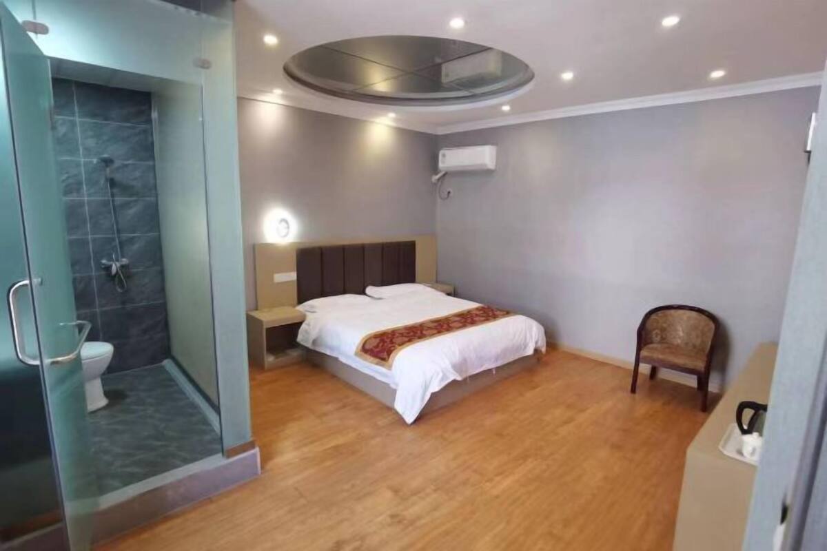 Une chambre moderne dotée d’une douche en verre, d’un lit avec une tête de lit, d’une table de chevet et d’une chaise.