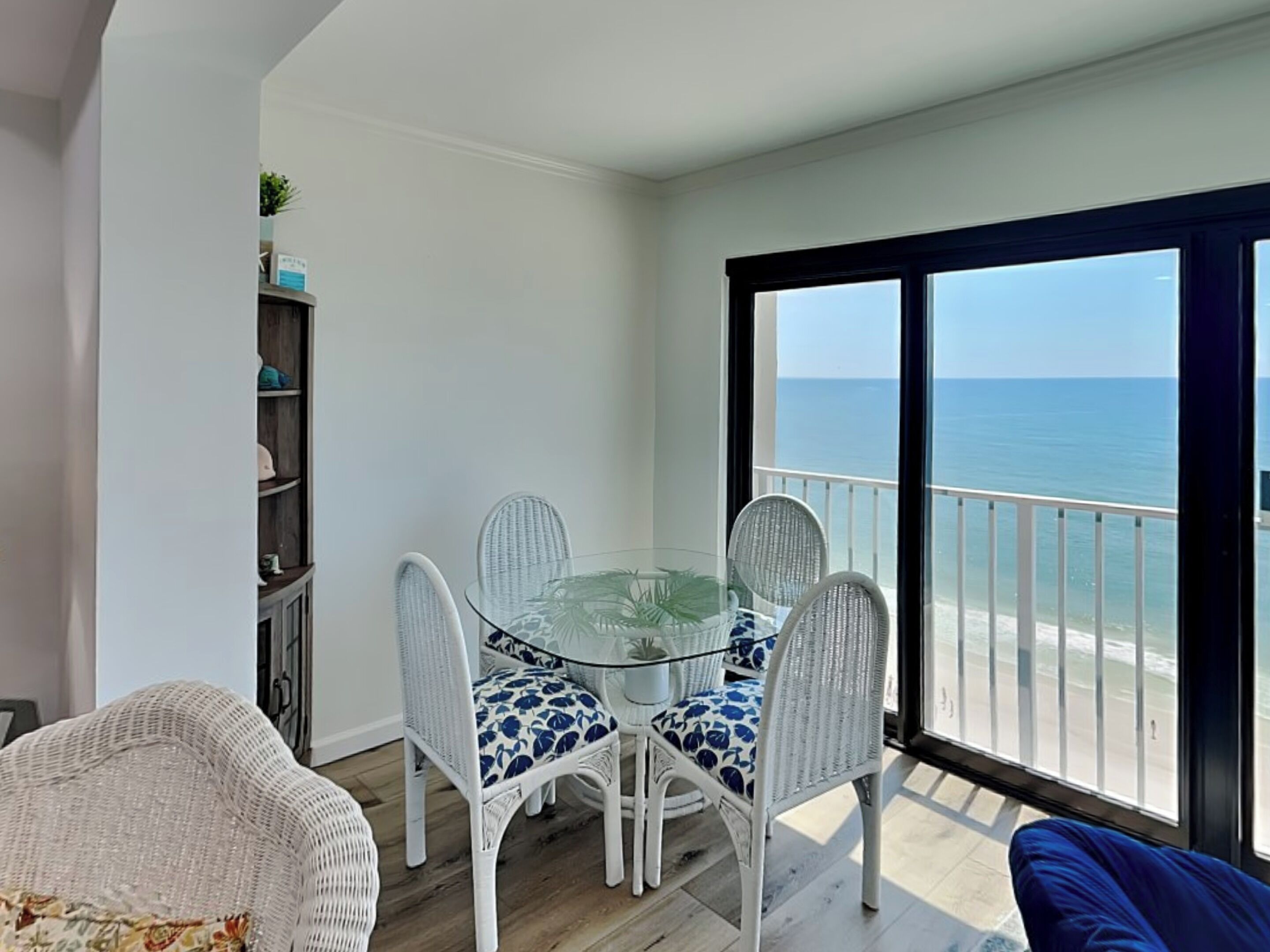 Un balcón con mesa y sillas de vidrio, con vista al mar.