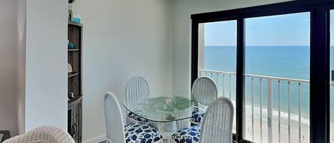 Un balcón con mesa y sillas de vidrio, con vista al mar.