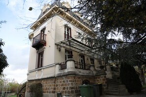 A historic building with a stone facade, a balcony, and a staircase leading to the entrance.