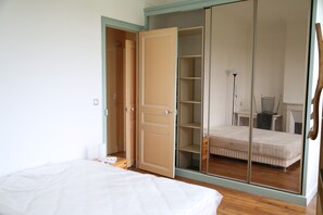 A bedroom with a bed, a wardrobe with a mirror, and a bedside table.
