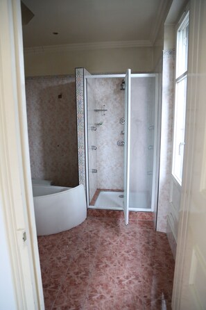 A bathroom with a shower enclosure, a bathtub, and a tiled floor.