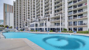 Un hotel moderno con piscina, varios balcones y vistas de edificios circundantes.