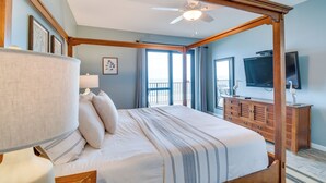 Un dormitorio con cama con dosel, ventilador de techo, cómoda y televisor en la pared.