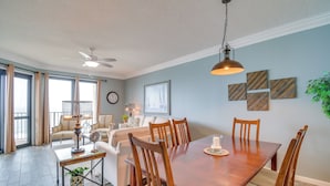 A dining area with a wooden table, chairs, and a ceiling fan. - Newly Renovated Oceanfront Orange Beach Condo! (Orange Beach)