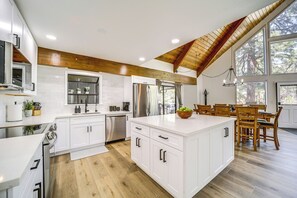 Une cuisine moderne avec des meubles blancs, des appareils en acier inoxydable et un plafond en bois.
