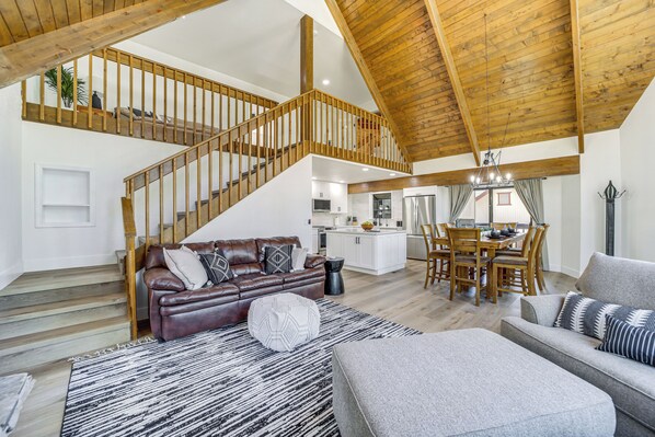 Un vaste espace de vie doté d’un haut plafond, d’un escalier en bois, d’un coin repas et d’une cuisine.