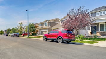 A residential street with houses, a red SUV, and a clear blue sky.
