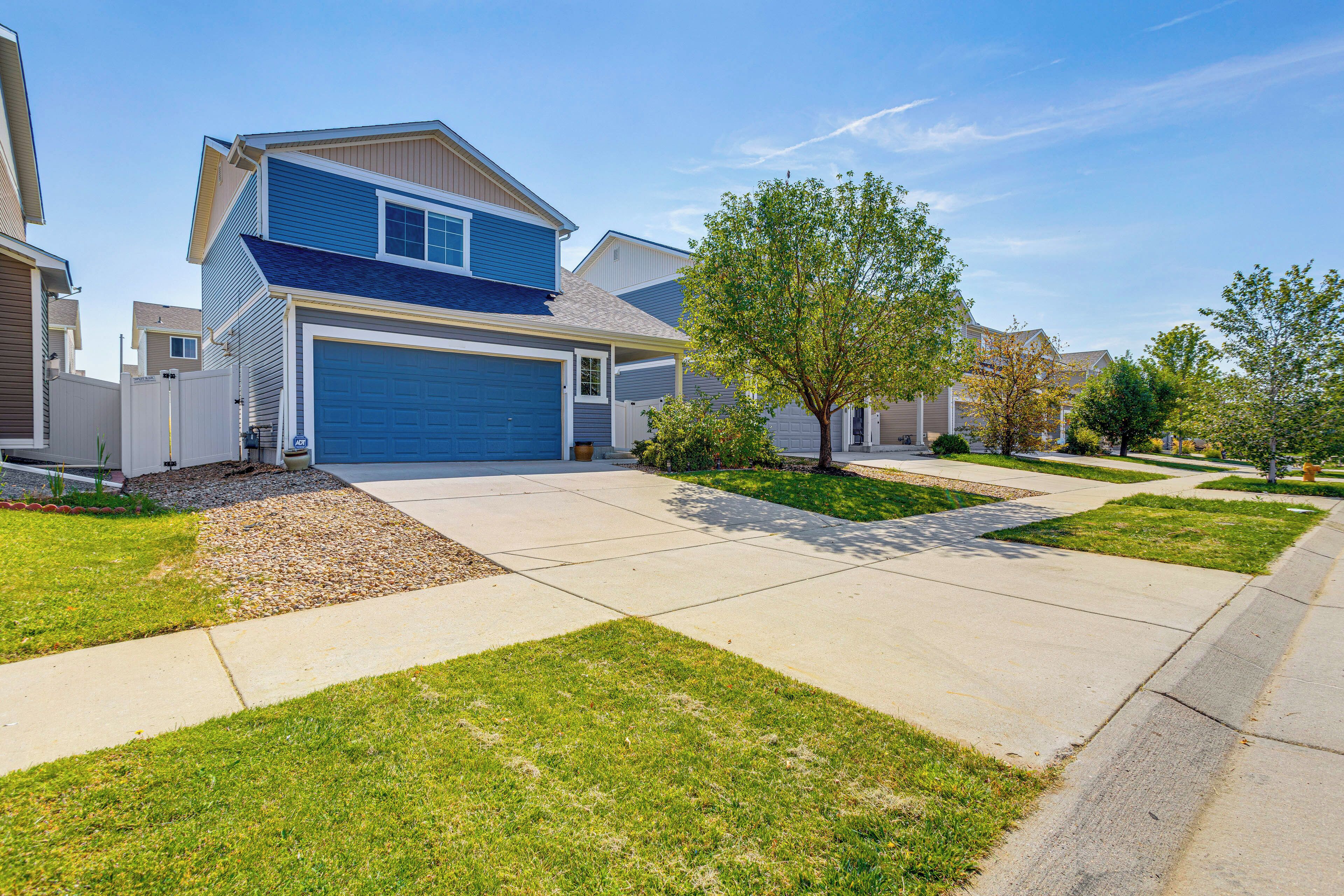 A modern two-story house with a blue garage door, a covered front porch, and a well-maintained lawn.