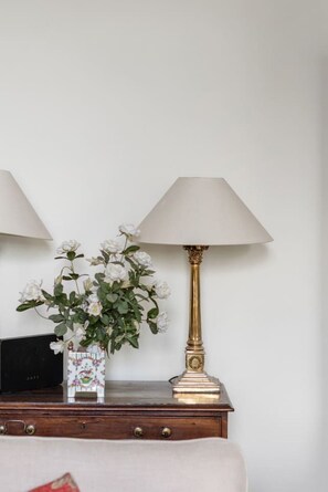 A bedside table with a decorative vase of white flowers and a classic lamp with a gold base.