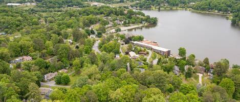 An aerial view of a residential area with a large lake, surrounded by dense greenery and hills in the background.