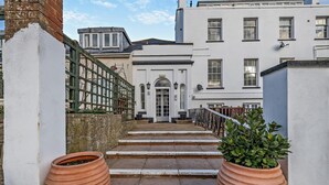 A set of stone steps leading to a white building with a traditional entrance and a green metal railing.