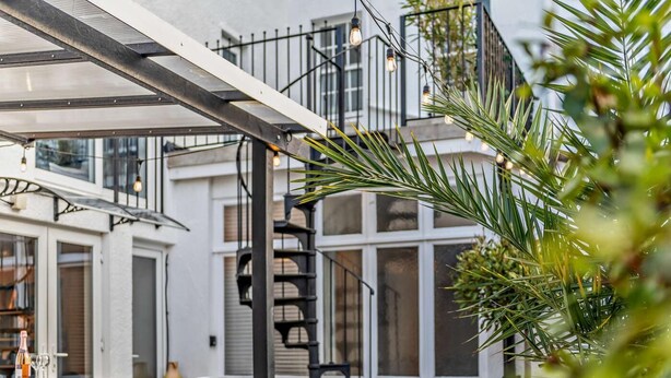 A modern building with a glass facade, a black metal staircase, and outdoor seating.