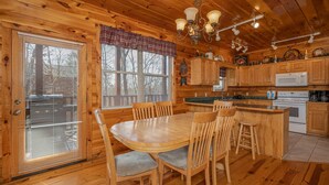 A wooden cabin-style kitchen with a central dining table, wooden chairs, and a built-in island.