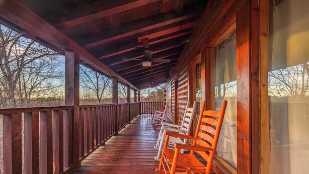 A wooden porch with rocking chairs and a view of the surrounding landscape.