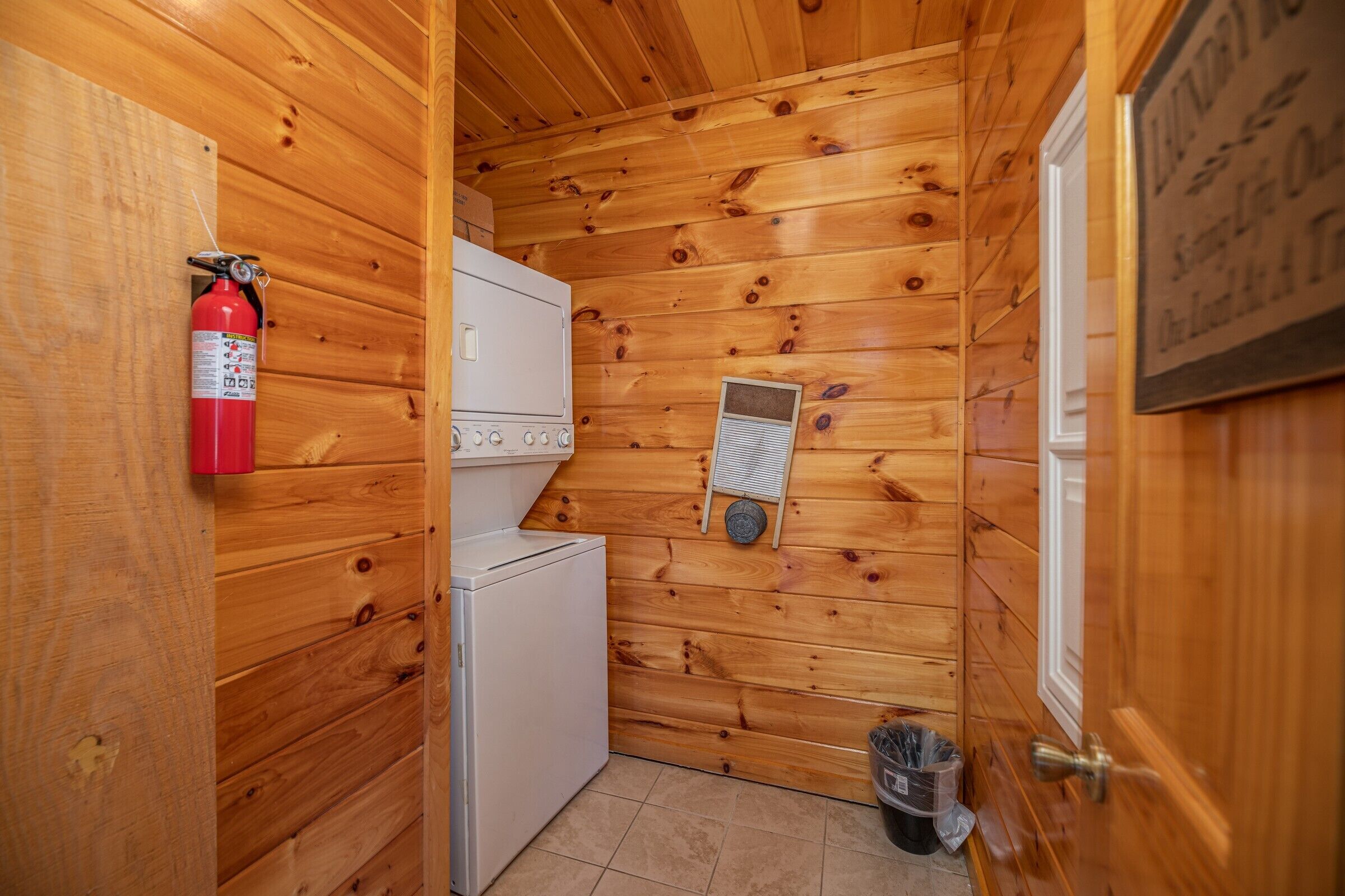 Una compatta casetta in legno con un angolo cottura, un estintore e una porta con un cartello.