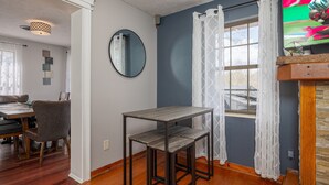 A dining area with a table and chairs, a mirror on the wall, and a window with curtains. - Recreational Playing One On One (SEVIERVILLE)