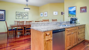 A kitchen with wooden cabinets, a granite countertop, and a dishwasher. - Charming 2-bedroom condo! (Rossland)