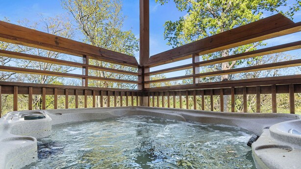 Un espace avec un jacuzzi, doté d’une terrasse en bois et de murs en pierre.
