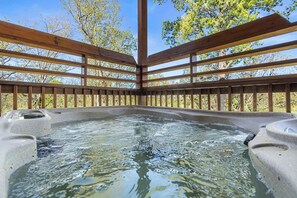 A hot tub area with a wooden deck and stone walls. - Private Pool Party Bliss (PIGEON FORGE)