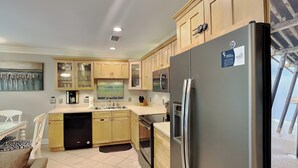Eine moderne Küche mit Holzausstattung, einem Edelstahl-Kühlschrank, einem Geschirrspüler und einem Essbereich mit Tisch und Stühlen.