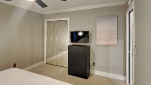 Ein Schlafzimmer mit einem Bett, einem Fernseher auf einem Schrank, einem Kleiderschrank und einem Deckenventilator.