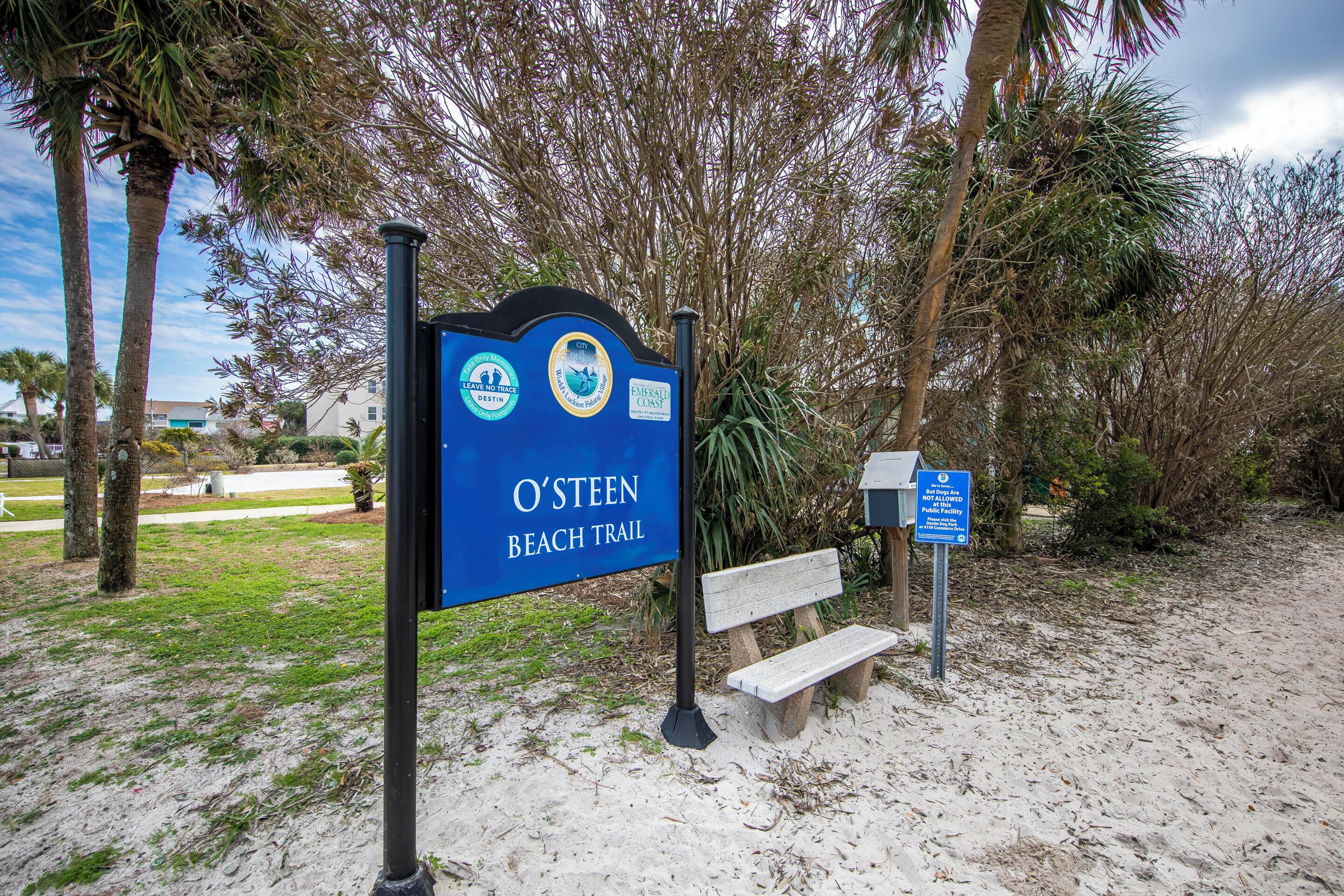 A beach trail sign with a bench nearby.