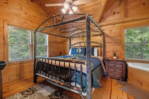 Une chambre à coucher dans une cabane en bois, avec un lit à baldaquin, une commode en bois et une fenêtre donnant sur les arbres.