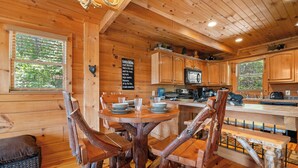 A wooden cabin interior with a dining table, chairs, and a kitchen area. - Gated Resort*Complimentary Wifi*Mtn. Views*Seasonal Pool (SEVIERVILLE)