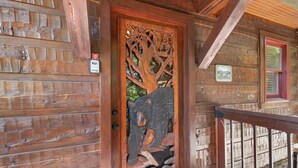 A wooden door with a carved bear and tree design, a wooden staircase, and a stone wall. - Gated Resort*Complimentary Wifi*Mtn. Views*Seasonal Pool (SEVIERVILLE)