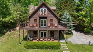 A two-story log cabin with a balcony, surrounded by trees. - Gated Resort*Complimentary Wifi*Mtn. Views*Seasonal Pool (SEVIERVILLE)