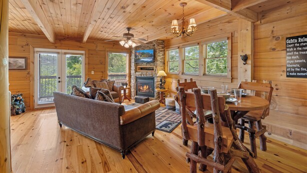 A cabin interior with a stone fireplace, wooden dining table, and a cozy seating area. - Gated Resort*Complimentary Wifi*Mtn. Views*Seasonal Pool (SEVIERVILLE)