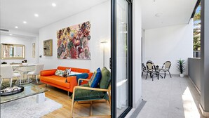 A modern living room with a glass door leading to an outdoor patio.