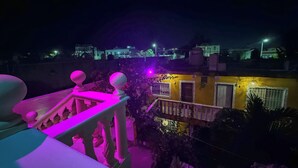 A balcony with a railing and a view of a yellow building with barred windows and a door. - Room for 3 people, 3 blocks from 5th avenue and public beach 🏖️🏝️ (Playa del Carmen)