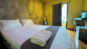A hotel room with a large bed, a small desk, a mirror, and a view of the outdoors. - Room for 3 people, 3 blocks from 5th avenue and public beach 🏖️🏝️ (Playa del Carmen)
