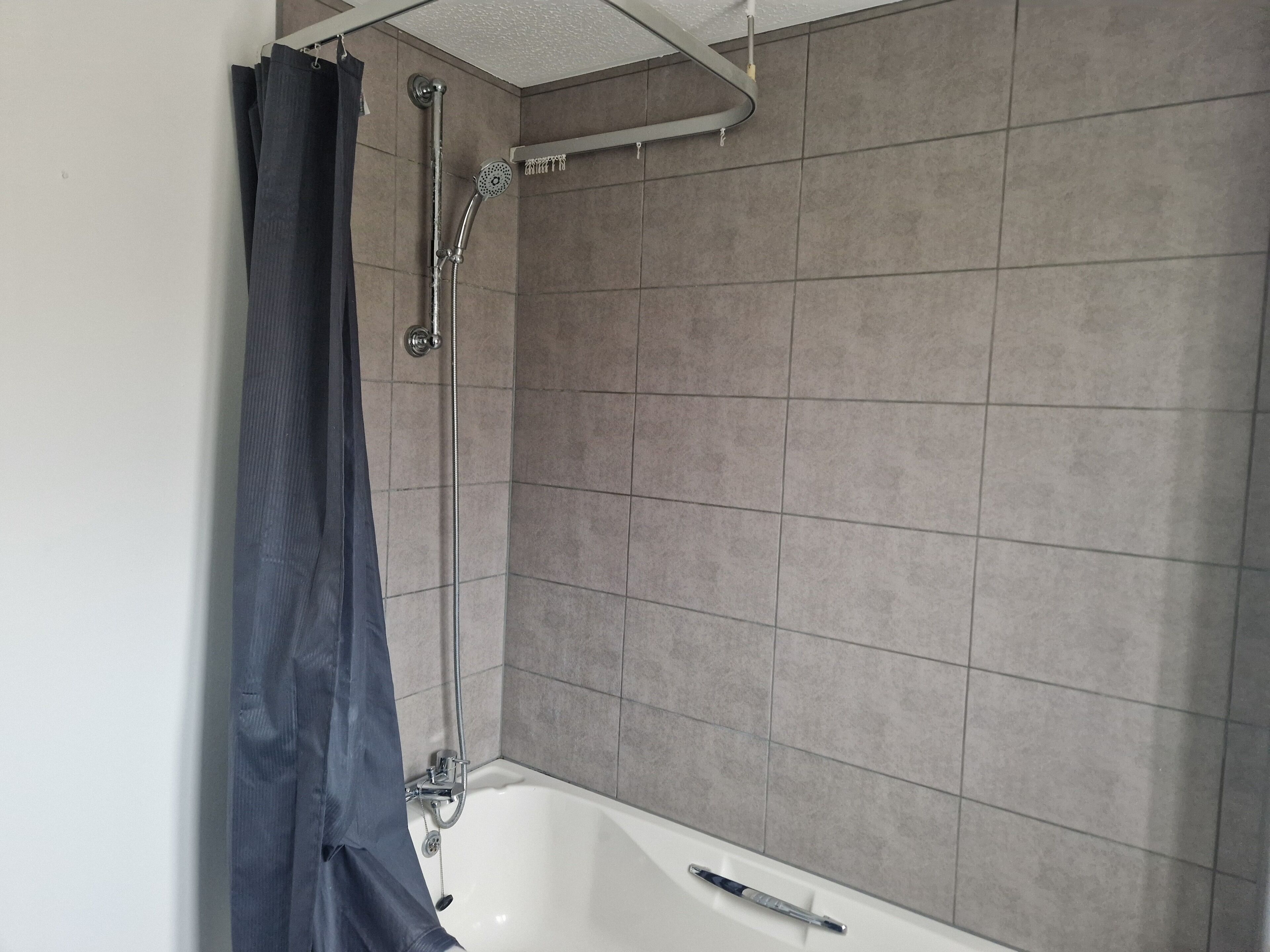A bathroom with a bathtub, shower, and tiled walls.