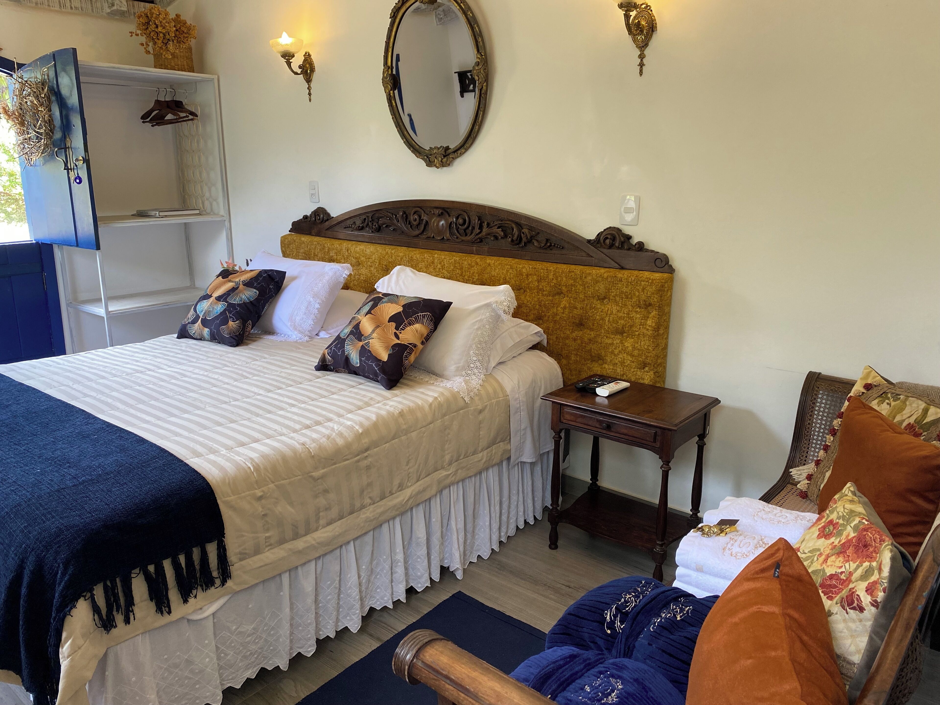 A neatly arranged bedroom with a large bed, bedside tables, a dresser, and a mirror.