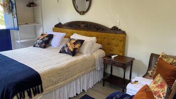 A neatly arranged bedroom with a large bed, bedside tables, a dresser, and a mirror.